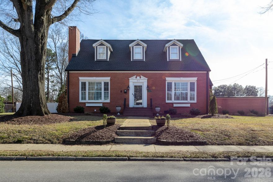 Step into a true piece of Kings Mountain history at 813 W. Mountain Street, where timeless character and thoughtful upgrades come together seamlessly.  Built in 1907, this remarkable home is rich in history, highlighted by a grand family room that once served as a ballroom, featuring original hardwood floors that run throughout the main level.  Expansive windows in the family and dining rooms fill the home with natural light, enhancing its warmth and historic charm.  The main level offers two spacious bedrooms and two updated bathrooms, including a beautifully remodeled primary bath with a step-in tiled shower, updated flooring, and new vanity. Toward the rear of the home, a second family room with built-ins and a fireplace provides a cozy gathering space with access to the screened-in porch overlooking both the front and backyard.  Upstairs, you’ll find three spacious bedrooms, all with walk-in closets, along with a large, shared bathroom featuring a separate shower and whirlpool tub.  New carpet has been installed throughout the upstairs, adding comfort and a fresh, updated feel.  Designed for both everyday living and entertaining, the outdoor space is equally impressive. Situated on a private, fully fenced 0.75-acre lot, the backyard features an 18’ x 36’ in-ground heated saltwater pool and spa surrounded by additional concrete, professional landscaping, and a paver patio with wired low-voltage landscape lighting. The pool system is equipped with a variable-speed Hayward OmniLogic system, allowing you to control temperature, spa settings, and multicolor lighting directly from your phone. A high-end Dolphin M600 WiFi-enabled robotic pool cleaner (for in-ground pools up to 50 feet) will convey for effortless maintenance.  Privacy and convenience have also been prioritized with a 6-foot vinyl privacy fence enclosing the entire backyard, along with a 16-foot steel gate featuring a LiftMaster gate opener and wireless gateway for remote access through the myQ app. A separate wired storage building with its own meter has been reconnected to power and brought up to current safety code, offering flexible use for storage, hobbies, or a workshop.  The home has been thoughtfully improved for both efficiency and long-term peace of mind, including crawlspace upgrades with a new sump pump, sealed vents, vapor barrier, and commercial-grade dehumidifier, replacement of multiple plumbing lines, a new sewer line with cleanouts, and a new water line from the house to the road. Additional updates include a new architectural shingle roof including all new flashing and sheething, Hardie® board siding on all dormers with new metal trim, and re-screening of the side porch.  This one-of-a-kind property offers historic charm, functional space, and an ideal setting for entertaining—all in a beautiful, established setting.