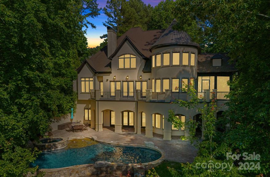 Enjoy lake views year-round at this private, waterfront retreat tucked away down a beautiful meandering driveway. Grand in stature & design, the home features over 9,000 sq. ft. of living space on 3 levels, connected by an interior elevator, with lake views throughout. The open-concept main level includes a classic den/study off the entry; great room w/gas fireplace, floor-to-ceiling built-ins, & beautiful coffered ceiling, open to the gourmet kitchen w/ oversized island, large dining area, & access to screened patio & balcony. Enjoy the added conveniences of a built-in espresso machine, warming drawer, & refrigerated beverage drawers. The Primary on the main includes a spa-like ensuite, laundry area, & dry bar. Upper: Computer niche, 3 large Guest bedrooms (2 w/ensuites); Bonus w/fireplace & wet bar; Laundry; Full bathroom. Lower: Huge "Rec-room" w/fireplace, 2 Bed/Bonus rooms - 1 connects to the gym, 2nd kitchen, Wine Cellar, Media Room, & outdoor access to the Terrace, Pool, & Lake!