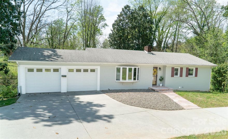 Enjoy the best of both worlds in this beautifully updated 1960s in-town ranch—offering exceptional privacy while being just a short walk to downtown Morganton and the popular Forest Hill Elementary School. Thoughtful upgrades by the current owner include converting the carport into a two-car garage, installing updated windows throughout, and finishing the basement to create an additional spacious great room and laundry area. The exterior shines with freshly painted brick, new shutters and storm doors, plus an extended driveway for additional parking and a new storage shed.