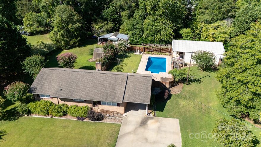 Welcome to your dream home! This charming 3-bedroom, 2-bath all-brick ranch is nestled on a spacious 0.85-acre lot. The property features an attached carport, an inviting in-ground pool, a detached garage/workshop, a shed, and a greenhouse. Inside, you'll find plantation shutters, a large living room, and a great room with a cozy fireplace and gas logs. The kitchen boasts a breakfast bar and hardwood floors extend throughout the living areas. Enjoy the practicality of a large laundry area, which is heated and cooled, accessible from the carport. The deck is perfect for outdoor entertaining with a gas grill hookup, and the pool area is securely fenced. Conveniently located with easy access to shopping, dining, entertainment, and the interstate. Don't miss out on this fantastic opportunity!