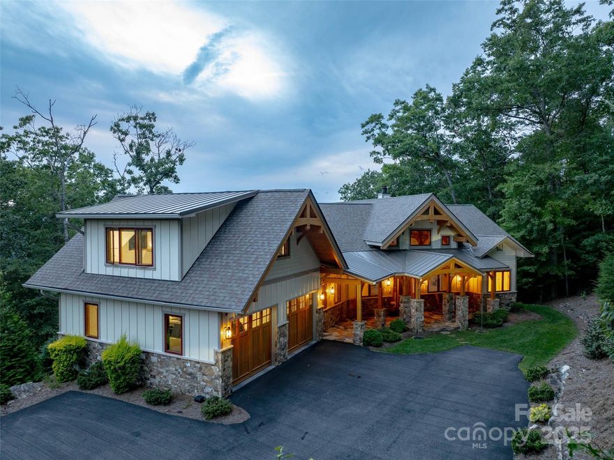 Nestled near the prestigious Champion Hills Golf Course community of Hendersonville, North Carolina, 1303 Solomon Circle is a masterpiece of architectural brilliance and refined luxury. This custom Timber Frame Hybrid residence, set on a rare 2.91-acre lot offers stunning long-range mountain views. Crafted with Douglas Fir interiors and Cypress beams, the home blends timeless craftsmanship with modern innovation, creating a sanctuary of comfort and sophistication. Spanning over 2,200 square feet on the main level, it embodies meticulous design and environmental harmony, delivering a lifestyle of elegance and serenity. The newly resealed driveway, framed by river rocks for soil retention and drainage, leads to a striking exterior sealed with Perma-Chink stain, harmonizing with the forest. SIP 6-inch walls ensure exceptional energy efficiency, surpassing Energy Star standards, while a Brazilian HVAC unit with variable speed control, heat exchange system, and Stratus fan provides year-round comfort. A 16 kW Generac generator ensures uninterrupted power. Recent landscaping, including Green Giant Arborvitae and a powder-coated aluminum fence enclosing 0.25 to 0.50 acres, creates a private oasis. A Trex deck with dog-friendly steps connects indoor and outdoor living, inviting residents to enjoy the mountain air. Inside, the Great Room features soaring timber beams, Douglas Fir interiors, and a stone masonry fireplace with concealed speakers, blending rustic charm with modern convenience. A gallery wall adds personal flair, making it a hub for gatherings. The open floor plan flows into the Kitchen and Breakfast Room, unified by wood ceilings and Cypress beams. Designed by House of Chloe, the kitchen boasts Wolf and Sub-Zero appliances, including a 42-inch refrigerator, Scotsman ice maker, and Asko dishwasher. Custom Walker Woodworking cabinets with leathered granite and a chef’s pantry create a functional yet inviting space. The Master Suite offers serenity with custom black metal and antique wave glass French doors opening to a private deck, ideal for enjoying sunsets over the Blue Ridge Mountains. The Master Bath features a walk-in shower with multiple heads, floor-to-ceiling marble, a frameless glass door, a soaking tub, dual vanities, and radiant heated marble floors, crafting a luxurious retreat. The Main Level Study, with Hickory floors, shiplap wainscoting, and unique lighting, serves as a refined workspace. The Powder Room, with a Mahogany and frosted glass door, custom vanity, and bold black accents, elevates intimate spaces. Outdoor living shines with a multi-level Trex decking system and stainless steel railings, offering unobstructed mountain views. The terrace level includes a Superior direct vent gas fireplace, a 300 GPM waterfall pump with UV filtration, a natural gas grill. The 30-year architectural shingle roof and metal accents ensure durability and style. The Terrace Level expands functionality with a Family Room, wet bar, two Guest Suites with en suite baths, an exercise room, wine cellar, root cellar, and utility room. The oversized 2-car garage, with epoxy floors and storage, connects to a 2022-upgraded Bonus Room with a kitchenette and modern bathroom, ideal for a mother-in-law suite or studio. The Laundry Room, with stunning tile, LG washer and dryer, and a custom folding table, blends practicality with elegance. From the Hickory hardwood floors to the intricate Cypress beams, every element of 1303 Solomon Circle reflects luxury. The dual-speed HVAC with heat recovery technology ensures efficiency, harmonizing old-world charm with modern comfort. This residence is a retreat, a statement, and a celebration of refined living, where nature and craftsmanship elevate every moment.