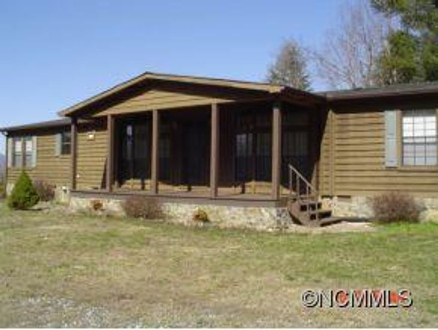 Wood-clad double wide in great location on a knoll with front and rear porches and forever views. Shoes pride-of-ownership. Gas fireplace, jet tub, oil heat and electric central air. Good carpet and laminate wood floors; wainscoating. Stove, refrigerator, washer and dryer convey. Out building for storage. EZ access. 45 minutes to AVL; 20 minutes to Marshall. Call LO for code to private lock box on gate. Vacant.