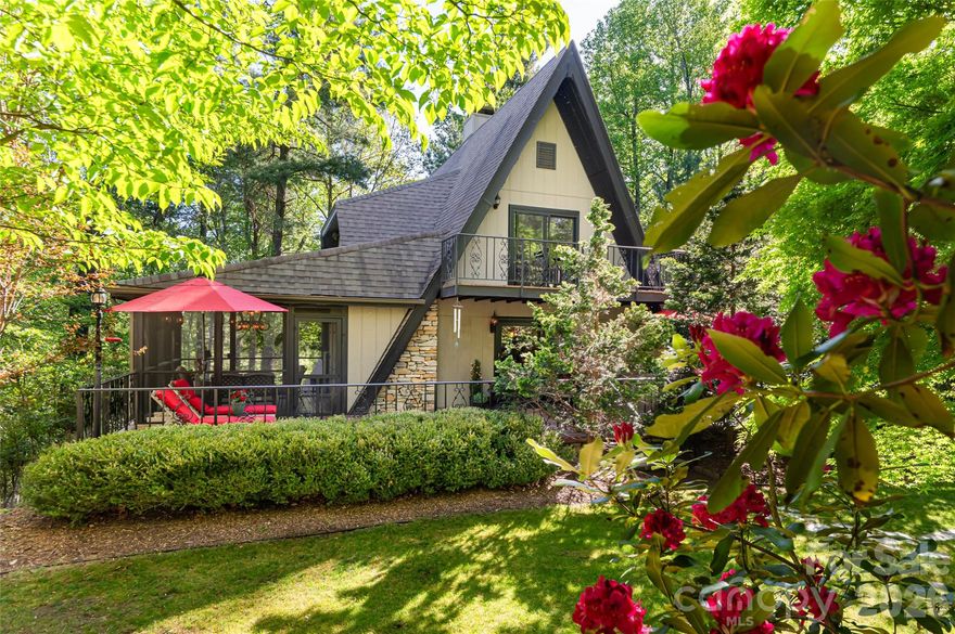 Tucked on a quiet cul-de-sac inside Champion Hills, Hendersonville's premier private golf community, this one-of-a-kind A-frame cottage is the kind of property that stops you in your tracks. Its distinctive alpine character is rare in the neighborhood, yet it feels at home in Western North Carolina: whimsical, charming and utterly peaceful. A stone walkway winds through beautifully landscaped grounds bursting with rhododendrons, azaleas and peonies to a handsome brick patio entry. Inside, an open-concept main level features a stone gas log fireplace, updated kitchen with granite countertops, Samsung appliances and a Blanco undermount sink. A screened sitting porch off the kitchen is ideal for morning coffee in a wooded setting. The main level also includes two bedrooms and a full bath. Upstairs, two more bedrooms share a full bath; the larger upper bedroom is a standout with a private balcony and a generous walk-in closet. The lower level delivers a large recreation room, wine room, laundry room with sink, half bath and ample storage, finished in tile and LVP throughout. Champion Hills is a private, member-governed community centered around Tom Fazio's acclaimed Mountain Masterpiece, ranked #1 among year-round courses in Western North Carolina. The 25,000-square-foot lodge-style clubhouse offers fine and casual dining, a heated pool, Hydro Spa, Har-Tru tennis, pickleball, fitness center and 17-plus miles of recreational trails. Over 100 social clubs and activities round out community life. Just eight minutes from award-winning downtown Hendersonville, with several grocery stores including The Fresh Market and Publix less than 10 minutes away.