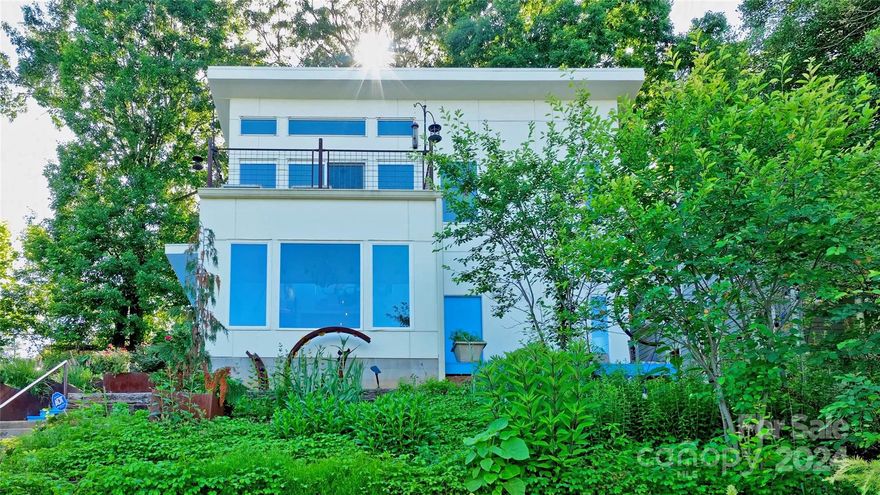 A light-filled contemporary refuge enhanced with custom artistic metal fixtures just steps from all cool things Asheville! Perched above the street & overlooking the downtown skyline there's a private feel to both this residence  & this West End Clingman Ave neighborhood (WECAN). Clerestory entry breathes air and light to both the main & upper levels with a spectacular custom steel banister linking the two floors. Updated, open kitchen with radiant concrete floors on the main, newer appliances, new minisplits, Murphybed & updated bathrooms including jacuzzi tub. Original owner incorporated craftsman features throughout: steel-framed mirror, wood & steel shelving, concrete & steel bath vanity & more. Take in the views from front upper & lower decks or enjoy the privacy in the backyard patio under spectacular oak trees & next to the cascading waterfall and pond. Fantastic opportunity to walk to the RAD, Grey Eagle, greenway & more! Furnished too!