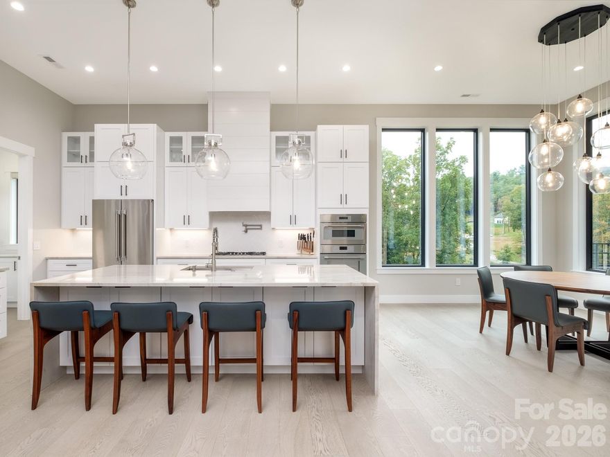Introducing an unrivaled opportunity within the exclusive, gated Horse Shoe Cove community. At 2.7 acres, this stunning modern retreat commands the largest and most desirable lot in the entire development, offering a level of privacy and ease of use that is a often sought, yet rarely found. 
A distant advantage of this property is its topography: a remarkable, perfectly level full acre of manicured lawn. This flat, usable terrain is a true unicorn in our mountainous region, providing immediate, ready-to-use space for gardening, play, or a future pool, perfectly complemented by the balance of wooded privacy.
The architecture and design brilliantly capitalize on the enchanting setting. This home is a testament to thoughtful design and coveted true one-level living, offering a seamless flow between the elegant interior and the flat, expansive grounds. Soaring 12-foot ceilings, 8-foot doors, and walls of windows flood the open floor plan with light and draw the eye toward the surrounding tranquility.

The great room is centered around a remarkable floor-to-ceiling custom stone fireplace flanked by elegant floating shelves, making the space ideal for both quiet nights and lively gatherings. The gourmet kitchen is a chef's dream, appointed with top-of-the-line Thermador appliances and anchored by a walk-in butler's pantry to keep the main space clutter-free for effortless entertaining.

The luxurious primary suite offers a private escape with an oversized walk-in closet and a spa-like shower and grand soaking tub. For supreme comfort, all bathrooms feature heated floors.

The home's greatest extension is the expansive screened-in patio, which acts as a second living room complete with its own stone fireplace, a built-in grilling station, and dining area. This outdoor sanctuary directly overlooks the level, fenced-in yard, confirming that the usable acreage is a natural, effortless extension of the living space. The attached three-car garage goes beyond the standard, offering impressive storage.

The location is unparalleled: a short drive to the vibrant scenes of Asheville, Hendersonville, and Brevard; minutes from the acclaimed Ecusta Trail; convenient proximity to Asheville Regional Airport (AVL) as well as a local hospital system recognized as One of America's 100 Best Hospitals for 2025. This is more than a home—it is an invitation to secure a premier, luxurious estate in beautiful Western North Carolina.