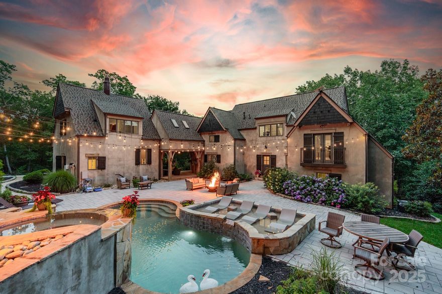 Gracious living awaits atop Little Mountain on nearly 12 private wooded acres, where this French Provincial estate—designed and owned by renowned architect Jim Phelps—offers timeless craftsmanship and refined luxury. Over 6,000 sq ft includes 4 beds per septic (many flex spaces) 5 full baths, a brand-new chef’s kitchen, and a private suite ideal for an au pair or in-law. Entertain effortlessly with a saltwater pool, tanning ledge, elevated waterfall spa, over 2,000 sq ft of patio, and dual gas firepits. Multiple balconies frame serene, wooded views, while a refined speakeasy with wet bar and fireplace adds a dramatic touch. The luxurious primary suite impresses with 22-foot ceilings, a stunning wall of windows, and a new spa-style bath featuring a steam shower, soaking tub, and wall-inset fireplace. A 30x50 metal barn offers flexible space ideal for a workshop, car collection, etc. A rare opportunity for elegant mountain living just under 40 min from the airport via NC 16 Hwy.