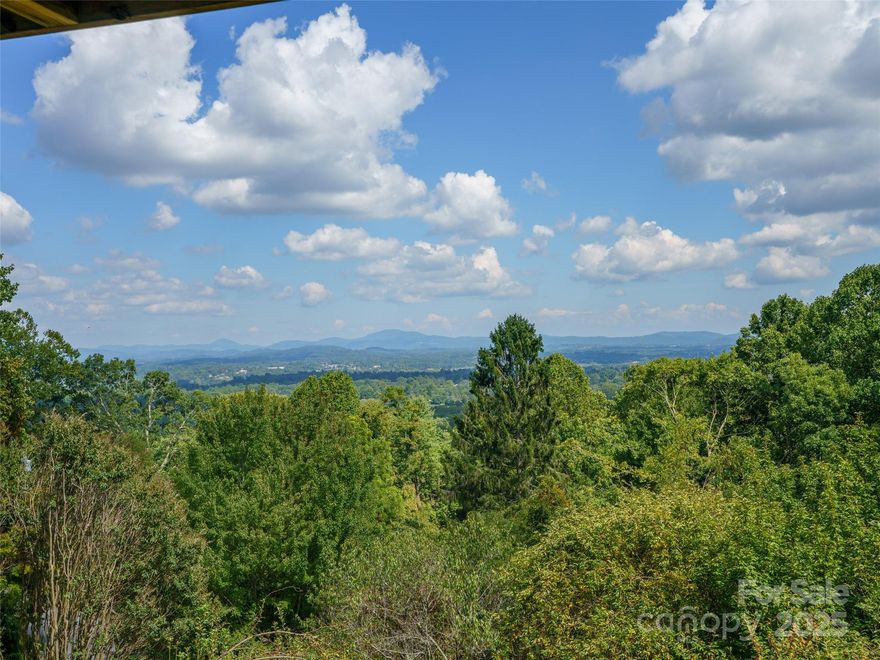 Discover the perfect blend of history and natural beauty in this charming 1933 home nestled on 2.10 acres in coveted Laurel Park. This unique property offers breathtaking east/southeast views spanning magnificent mountain range and the town of Hendersonville in the distance. Believed originally constructed as an A-frame, the house was expanded in years past feeling remarkably spacious with high beam ceilings and tall windows flooding the interior with natural light. The living room and spacious porch are the heart of the home, showcasing stunning mountain vistas, cozy wood-burning fireplace, and expansive north-facing windows for bird watching. Main level also features bedroom/den and rustic dining room highlighted by a natural stone wall. Ground level offers an office and workshop (both unheated) and bedroom/bath w/separate entrances. The gently sloped property provides a nature lover's sanctuary with picnic area and rolling green space for outdoor enjoyment. A detached two-car carport has open storage. DISCLOSURE: In 2024 the exterior of the property sustained storm damage affecting portions of plumbing and septic, driveway, and carport roof. An "investigative permit" has been issued for the damaged septic.