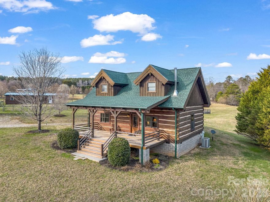 The beautiful craftsmanship in this Appalachian-style log home with hand hewn 14"-18" logs sets it apart from your average cabin!  This home sits back from the road and with almost 10 acres, it offers lots of privacy & possibilities!
Almost the entire property is fenced & cross-fenced, ready for your cows, horses, or goats. There's also a watering system for the animals in the pasture and there is a small stream at the back of the property.  Inside the home you'll find a large great room with wood burning fireplace, kitchen with cherry cabinets & granite countertops, the primary bedroom with 2 closets and a bathroom with double sinks and walk-in shower.  The laundry is also on the main level sharing space with a half bath.  Upstairs in the loft is a second BR & a full bath.  All appliances & most furniture will convey with the home. New roof & gutters in 2025 Outside you will love the view from the large 30 ft. covered porches on both the front & back of the home.  There's a very nice 48 X 26 building with electric used as a workshop that could possibly be converted back to a barn that also has a new roof & gutters. There's another barn plus two other nice storage buildings. This is a must see property!  Only one mile from US Hwy 74 for easy commutes to Asheville or Charlotte and it's only 16 miles from the Tryon Equestrian Center. Don't miss this one!