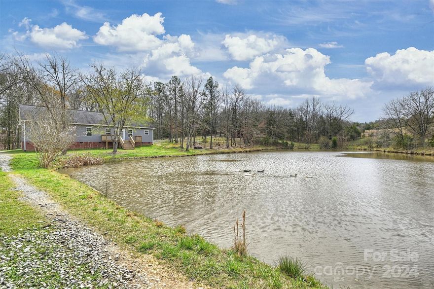 Amazing opportunity to own a truly beautiful 57-acre private, creekfront retreat in Blackstock, SC - just south of Rock Hill! Follow a tree-lined drive to discover a charming 3 bedroom, 2 bath ranch overlooking a stunning private pond. The back of the property is on Little Rocky Creek. There is a spacious family room with vaulted ceiling, kitchen with granite counters, breakfast bar, stainless appliances, and plenty of cabinetry, a spacious primary suite with private bath and walk-in closet, 2 generous size secondary bedrooms, a full bath and a laundry/mud room. Plenty of additional exterior structures for storage and maintaining the land include an outbuilding, chicken coop, barn, and a single wide mobile home(used as storage building). Enjoying the outdoors is easy on the rear deck that overlooks a private pond and 57 acres of woods to explore, ride your ATV, and enjoy!  This location is just 2 miles from I-77 (Exit 55) and is close to the Great Falls White Water Park.