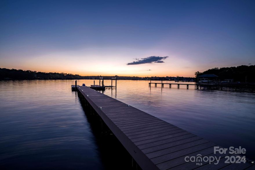 Experience luxury at this extraordinary Lake Norman estate. Enjoy stunning sunset and open water views for miles. Situated on a rare, flat lot with nearly 100 feet of shoreline, this home features a luxury brick seawall for unparalleled lakefront living. With no HOA, enjoy freedom and privacy. The new dock with Wolf decking includes a boat lift and deeper water access. Meticulously maintained, this home has a new roof, newer HVAC units, and epoxy floors. Large windows provide water views from almost every room. The spacious kitchen boasts granite countertops, and a stylish tile backsplash. Custom new wet bar. The luxurious primary suite features a walk-in shower and heated floors for ultimate comfort. Modern conveniences such as an invisible fence ensure peace of mind for pet owners. Every inch of this Lake Norman home is thoughtfully designed and maintained. Combining luxury, comfort, and natural beauty, this lakeside paradise awaits you.