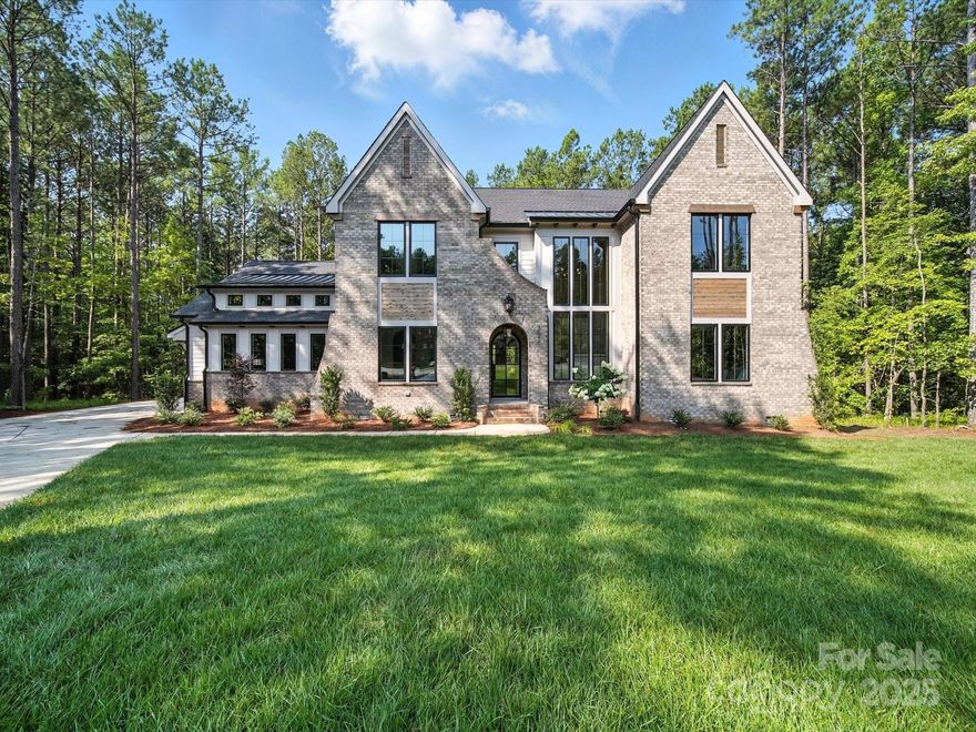 Embrace luxury at this stunning estate nestled among mature trees, adjacent to a 500-acre nature preserve. Curved portico with steel front door invites you inside where the expansive wall of windows fills the home with natural light, accentuating the beautifully finished white oak floors, staircase, and meticulously designed spaces throughout. Chevron inlay trey ceilings accentuates the carefully designed kitchen, living room, dining room, and owner’s suite. Owner’s suite boasts custom arched alcove windows, while the owner’s bathroom offers distinct vanities for personal space. Enjoy a spacious bonus room complete with a bar and a separate area suitable for flexible living space. Full ensuite on main level for guests. Additionally, two walk-in storage areas are available for conversion into livable space. The large back porch, equipped with a fireplace, provides a perfect retreat for unwinding in privacy. Gated community offers multi-million dollar clubhouse with high end amenities.