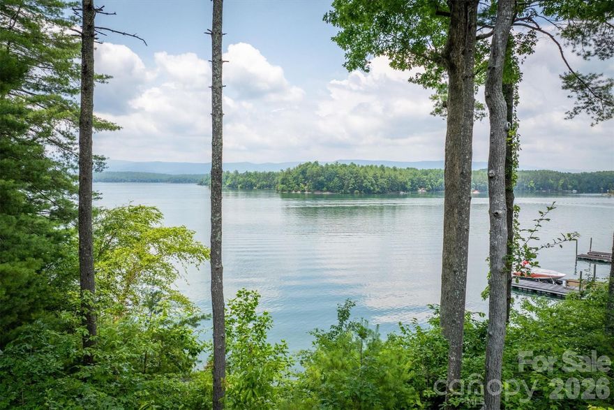 One-of-a-kind property situated on its own peninsula on beautiful Lake James in the sought-after South Pointe community. This amazing custom home sits on 2 acres with rear and side panoramic views of open water and the Blue Ridge Mountains, including Shortoff and Table Rock Mountain. High-end features include oversized windows, custom-tiled showers, granite countertops, a butler’s pantry, outdoor shower, real hardwoods, superior wall basement, 50-year shingles, electric water heaters, and more! Open-concept living, dining, and kitchen areas sit under a cathedral ceiling with a huge stacked rock fireplace and floor-to-ceiling rear windows. The large primary suite features two walk-in closets and a luxury ensuite bathroom with a custom-tiled shower, jacuzzi tub, and exterior entry. A second bedroom on the main level offers an adjacent full bath. The upper level includes an open loft/second living area and a second primary bedroom with a spacious full bath featuring a jacuzzi tub. The basement can be accessed from the interior of the main home and the detached garage via a covered walkway. Enjoy a true oversized garage with a work area. The massive unfinished basement features storage rooms, a family room with a second fireplace, high ceilings, and a full bath. Above the garage, with private entry, is a studio apartment complete with a closet, kitchen, and full bath. Words can’t describe the grounds… a rocked trail wraps around the point, offering lake views from the back and both sides. Even better, enjoy an easy stroll to your own private covered lakefront deck and composite dock.