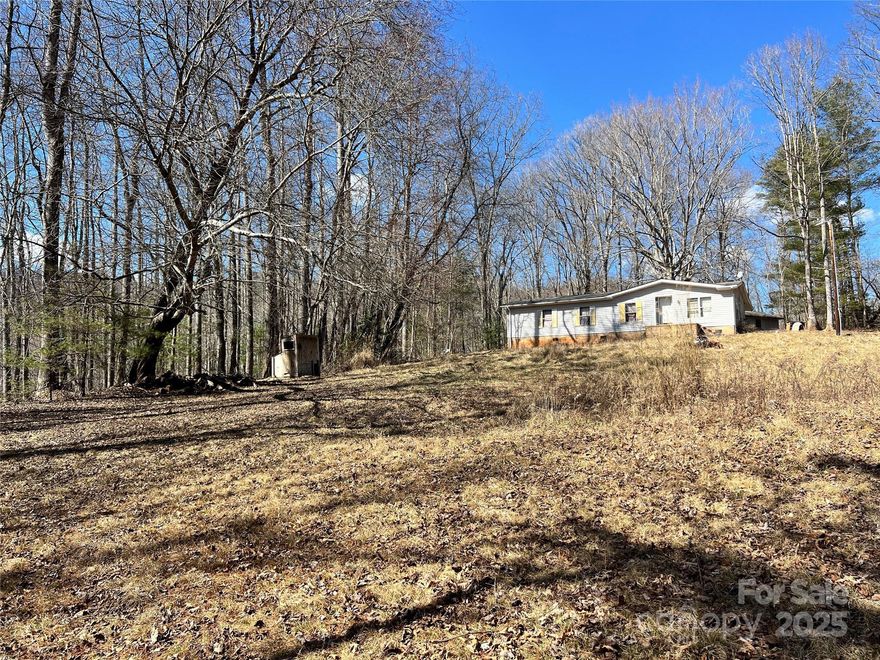 Versatile property with endless potential, featuring mostly cleared, level land and scenic winter views and creek along property line. Ideal for outdoor enthusiasts, this spacious lot offers ample opportunities for recreational use, a private retreat, or potential subdivision for multiple homesites (buyer to verify). The existing manufactured home is in disrepair but includes a well and septic system; seller makes no representation regarding their condition. Enjoy the perfect blend of privacy and convenience—located just 20 minutes from both Asheville and Hendersonville, and only 10 minutes from Asheville Regional Airport. A rare opportunity to create your dream space in a prime location!