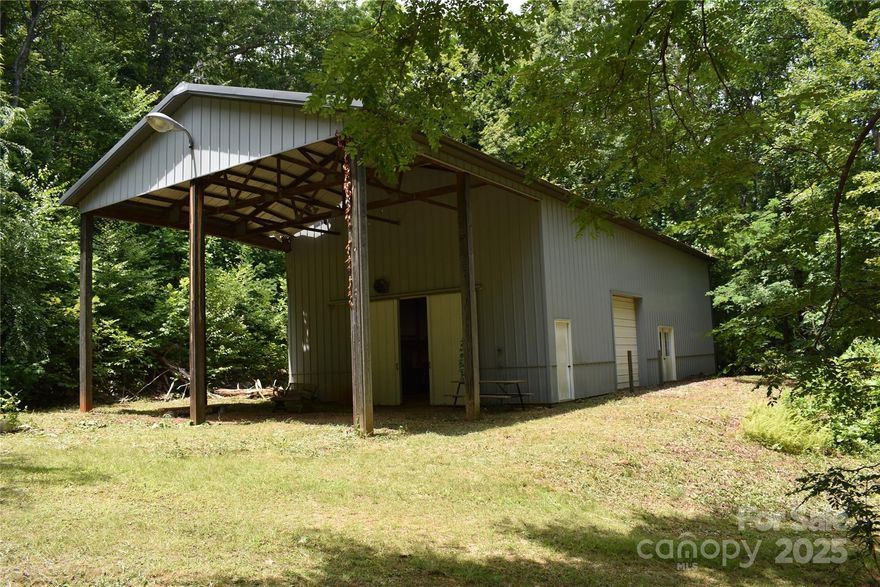 *****Just Reduced**** Up for sale is a 5.4 acre portion of a larger 14.84 acre parcel, that is about 1.5 miles from the New NC State Park in Candler, the Blue Ridge Parkway and it also borders property that borders the  Pisgah National Forest lands. Already in place is a metal building 30x60 with a rollup door and barn style doors opening to 9 1/2' high.  The building has wall insulation and a floored loft area with adds an additional 675 sf. Bathroom is in place and electrical service has higher amp plugs, and lighting. There is a 23x30 covered area and plenty of parking area. The metal building would make a great barndominium, Airbnb, or a working studio. Zoning is open use, so the possibilities are pretty much endless. The private road to property is narrow and might be difficult for larger delivery type vehicles to navigate. There is spring water currently and a no septic system. Several areas are suitable for a future home site, and the metal building can accommodate equipment & vehicles