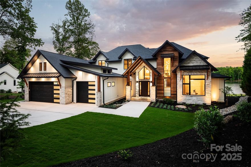 Colorado-inspired Luxury on Lake Norman! This 5BR, 4.5BA custom home offers 250 ft of shoreline, a rare private boat ramp, and large, breathtaking 180° views. Inside, custom craftsmanship shines with dramatic feature walls and a soaring 2-story cedar coffered ceiling. The chef’s kitchen features a massive 10x5.5 island with 3” Taj Mahal quartzite and instant hot water throughout. The primary suite includes 12’ ceilings, spa-style marble bath with heated floors, freestanding tub, zero-entry smart shower, and private owner’s laundry. Hardwood floors flow throughout, with media and workout/flex rooms, a 40-year roof, encapsulated crawlspace, and oversized 3-car garage with epoxy floor. Outdoor living shines with a heated saltwater pool/spa, silver travertine patios, 20x25 firepit patio, grilling station, timber framed porches, and extensive landscape/hardscapes. Lake-fed irrigation, sunset views, no HOA, and minutes to I-77 & Hwy 16.