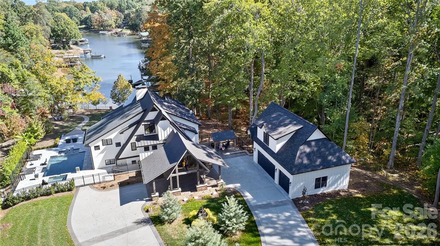 A unique, luxury A-Frame on almost a 2-acre lot is a remarkable offering on Lake Norman with over 700 feet of pristine shoreline. Perfect for short-term rental, second home, or primary residence -with a successful short history as a high-end vacation rental, this property presents a rare opportunity to own an incomparable lakefront estate. A showstopping waterfront estate was meticulously reconstructed in 2023—taken down to the foundation and rebuilt as the personal primary residence of a luxury homebuilder. This private retreat embodies timeless design, elevated living, and masterful craftsmanship.  Enter through a dramatic custom waterfall feature into a light-filled, open interior designed for both effortless entertaining and everyday indulgence. Every detail has been intentionally curated, including designer lighting, multiple fireplaces, elevator access to all levels, and top-tier appliances. The main-level primary suite provides a serene retreat with picturesque views of Lake Norman and direct access to the covered deck. The luxurious ensuite features an oversized tiled shower, a freestanding soaking tub, a spacious dual vanity, heated tile floors, and a large walk-in closet outfitted with a custom organizer. Additional bedrooms and laundry rooms on each floor provide optimal comfort and convenience. The outdoor environment is equally extraordinary, featuring a heated pool and spa surrounded by travertine, a gas fire pit, lush professional landscaping, architectural lighting, and an irrigation system. The newly updated 2024 dock and kayak stand. Provides effortless access to the water from the beach area -perfectly enhancing the lakefront lifestyle. A detached three-car garage with an unfinished upper level, complete with pre-plumbing, along with an expansive circular driveway and an elegant porte cochere, complements this exceptional property.