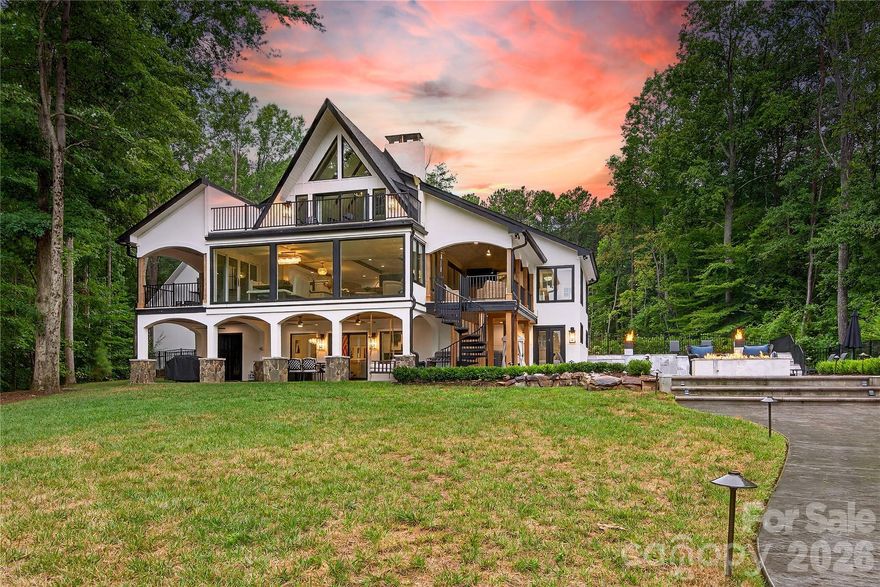 New Price! Modern, luxury A Frame on almost a 2-acre lot is a remarkable offering on Lake Norman with over 700 feet of pristine shoreline. A unique and showstopping waterfront estate was meticulously reconstructed in 2023—taken down to the foundation and rebuilt as the personal residence of a luxury homebuilder. This private retreat embodies timeless design, elevated living, and masterful craftsmanship. Perfect as a primary residence, second home, or investment property -with a successful short history as a high-end vacation rental, this property presents a rare opportunity to own an incomparable lakefront estate.  Enter through a dramatic custom waterfall feature into a light-filled, open interior designed for both effortless entertaining and everyday indulgence. Every detail has been intentionally curated, including designer lighting, multiple fireplaces, elevator access to all levels, and top-tier appliances. The main-level primary suite provides a serene retreat with picturesque views of Lake Norman and direct access to the covered deck. The luxurious ensuite features an oversized tiled shower, a freestanding soaking tub, a spacious dual vanity, heated tile floors, and a large walk-in closet outfitted with a custom organizer. Additional bedrooms and laundry rooms on each floor provide optimal comfort and convenience. The outdoor environment is equally extraordinary, featuring a heated pool and spa surrounded by travertine, a gas fire pit, lush professional landscaping, architectural lighting, and an irrigation system. The newly updated 2024 dock and kayak stand. Provides effortless access to the water from the beach area -perfectly enhancing the lakefront lifestyle. A detached three-car garage with an unfinished upper level, complete with pre-plumbing, along with an expansive circular driveway and an elegant porte cochere, complements this exceptional property.