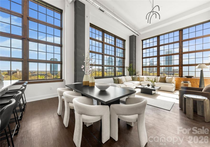 Welcome to The Penthouse at The Garrison at Graham—one of Uptown Charlotte’s most distinctive and architecturally striking residences. Occupying the prime top-floor corner of the building, this remarkable three-story penthouse spans approximately 2,750 square feet of sophisticated loft-style living and is framed by two dramatic walls of 12-foot floor-to-ceiling windows that flood the home with natural light while showcasing breathtaking panoramic views of the Uptown Charlotte skyline. With the touch of a button, motorized shades reveal sweeping city vistas that transform throughout the day—from morning light pouring into the living spaces to dramatic sunset and twilight skyline views. The main living level offers a truly impressive sense of scale with soaring two-story ceilings, expansive window walls, and rich wood flooring that flow throughout the open-concept living and dining areas. A gas fireplace anchors the living space, creating warmth and ambiance while maintaining a sleek modern aesthetic. The layout is thoughtfully designed for both everyday living and elevated entertaining. The chef’s kitchen serves as the heart of the home and features a massive center island with granite countertops, stainless steel appliances including gas range, oven, microwave, beverage refrigerator, dishwasher, and exhaust hood, along with abundant cabinetry and prep space ideal for hosting gatherings. The open floor plan seamlessly connects the kitchen to the living and dining areas, allowing guests to gather comfortably while enjoying the skyline views beyond the windows. The second level features two spacious guest suites or flexible office spaces, each with its own full en-suite bathroom, offering privacy and versatility for guests, work-from-home needs, or additional living space. A private sauna adds a spa-inspired element rarely found in Uptown residences. A mid-level flex space with an additional full bathroom offers even more versatility—perfect as a media lounge, secondary office, fitness room, or guest bedroom depending on your lifestyle needs. The top floor is dedicated entirely to the owner’s retreat, creating a private sanctuary above the city. This level features a generous primary suite, spa-like bathroom, and expansive walk-in closet, offering a quiet escape while still enjoying the dramatic skyline backdrop. The crown jewel of this penthouse is the extraordinary private rooftop terrace—your own “backyard in the sky.” Designed for elevated outdoor living, this expansive terrace includes a covered outdoor living room with gas fireplace, built-in stainless outdoor kitchen, and an artificial turf lounge area that creates a rare and inviting urban outdoor experience. Whether hosting sunset gatherings or enjoying quiet evenings overlooking the skyline, the terrace offers a truly unforgettable setting.Additional highlights include four assigned parking spaces in the secured garage (two primary spaces equipped with vehicle lifts), along with secure building access and gated entry, providing both convenience and peace of mind. The Garrison at Graham is a boutique luxury condominium building located in Uptown Charlotte’s historic Fourth Ward, known for its blend of modern loft-style architecture and neighborhood charm. Residents enjoy access to a shared rooftop social terrace featuring outdoor lounge areas, grilling stations, fireplaces, and sweeping city views, located conveniently on the same floor as the penthouse. Positioned along N Graham Street, the building offers exceptional walkability to Uptown’s vibrant lifestyle—including the NC Music Factory, professional sports venues, cultural attractions, restaurants, and nightlife—placing the very best of Charlotte’s urban energy just moments from your front door.