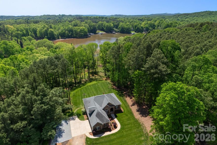Set on 5 acres, this custom home is nestled among the trees with a large cleared yard and Lake Wylie water views! Tall ceilings in the entry, living and dining areas create a bright, open feel, flowing into a well appointed kitchen with granite countertops, Bluestar gas range, Miele dishwasher, stainless appliances and an 800 gallon per day reverse osmosis system with UV filtration. The primary suite offers a quiet retreat with dual vanities, soaking tub, separate shower and a spacious walk in closet. The finished walkout basement adds flexibility with an additional bedroom, full bath and bonus space ideal for guests, office or gym, plus additional unfinished basement space perfect for storage or water gear. A large Trex deck overlooks the expansive yard and peaceful Lake Wylie water views. Water is not dockable but perfect for paddle boards, kayaking or canoeing. Upgrades include a Rinnai on demand water system, whole home generator, WiFi 6, integrated security with cameras, radon mitigation, epoxy garage floors and high efficiency Trane HVAC with whole house air filtration. Unfinished attic space already framed, plumbed and wired offers additional square feet for future expansion. Unincorporated location means no city taxes with easy access to I 485, the airport, shopping and the River District.