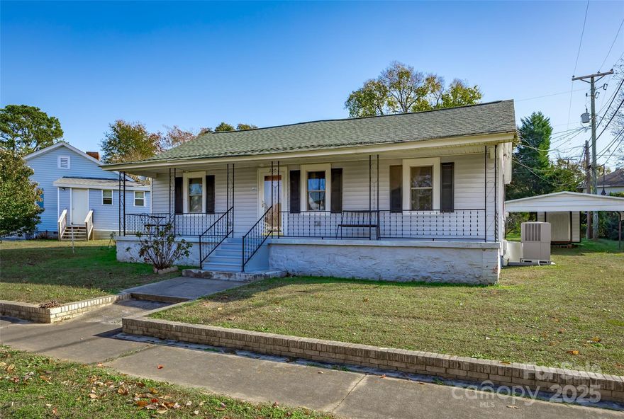 Tucked into the historic mill village of Winnsboro, this charming 1950s home offers an affordable path to homeownership for anyone ready to stop renting and start building equity. It sits in a neighborhood where people still chat from the front porch. Inside, you’ll find two comfortable bedrooms with warm wood paneling that gives a classic cottage feel, or easily update them with paint or a skim coat for a more modern look, keeping both the style and budget in your hands. The bathroom is tidy and functional with tile flooring and a traditional tub-shower combination. The kitchen feels bright with its fresh paint and ample cabinet storage, making everyday living simple and efficient. Years ago, a wall was opened to combine rooms and create a more spacious den in place of a third bedroom, giving you a surprisingly generous living area for an 800-square-foot home. A covered front porch brings the easy charm that mill homes are known for and offers a perfect spot for rocking chairs and neighborly conversation. Out back, the yard has room for a grill, small garden, or pets, plus a storage shed for tools and lawn equipment. Just 10 minutes to I-77, the home provides an easy commute to Columbia or Charlotte, and 20 minutes from the new Scout Motors plant. With Winnsboro positioned for growth, now is the perfect time to buy before prices rise. This home is ideal for anyone ready for a place to call their own, and the simple pride that comes from unlocking a front door that truly belongs to you.