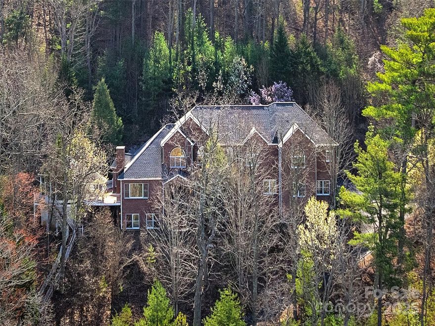 Grand estate on 7+ private acres with views of Beaver Lake and surrounding mountains. Towering high over Grove Park and Beaverdam Valley, this one-of-a-kind property gives the illusion of seclusion with its gates and pristine wooded setting while downtown Asheville is just down below. You are welcomed by a climbing driveway, brick terraced walls & walkways, and an elevated brick entryway. Inside, refined spaces & intimate nooks beckon entertaining & relaxation. Beyond the living room with sweeping views, you’ll find a kitchen with cherry cabinetry, island, eat-in nook, keeping room & access to the open wraparound deck & gazebo w/ hot tub. The primary suite stretches across the upper floor & features a double sided fireplace, sitting room and bedroom w/ access to a covered porch & elevated footbridge to the rear. Two main level BRs & a finished walk-out basement add versatile space for play, work & overnight guests. Separate, self-contained apartment with long-range mountain views.