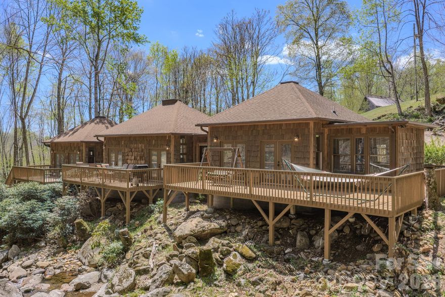 Escape to the quiet beauty of the mountains with this thoughtfully designed retreat, where peace and relaxation take center stage. Nestled in the serene landscape of Bakersville, this 2 bedroom, 2.5 bath home offers a perfect balance of comfort, privacy, and natural charm.

Inside, the inviting living space is complemented by warm wormy maple kitchen cabinetry and custom built-in benches with hidden storage blending functionality with timeless mountain character. Large windows invite the outdoors in, allowing you to take in views of the gently flowing creek while also hearing its soothing sounds from within the home creating a truly immersive, calming environment.

Outdoors is where this property truly shines! Three spacious independent private decks overlook the tranquil creek, offering the perfect setting for morning coffee, quiet reflection, or evening relaxation. A propane gas hookup makes outdoor dining effortless, while the warm-water exterior hookup provides the opportunity to create a spa-like outdoor shower experience.

A private walking trail runs alongside the creek, inviting you to stroll, unwind, and fully connect with the natural surroundings. The river rock driveway enhances the home’s organic beauty, welcoming you into a setting that feels both grounded and refined.

Whether you are seeking a weekend sanctuary or a place to fully disconnect and recharge, this property offers a rare opportunity to embrace the restorative beauty and peaceful rhythm of mountain living.