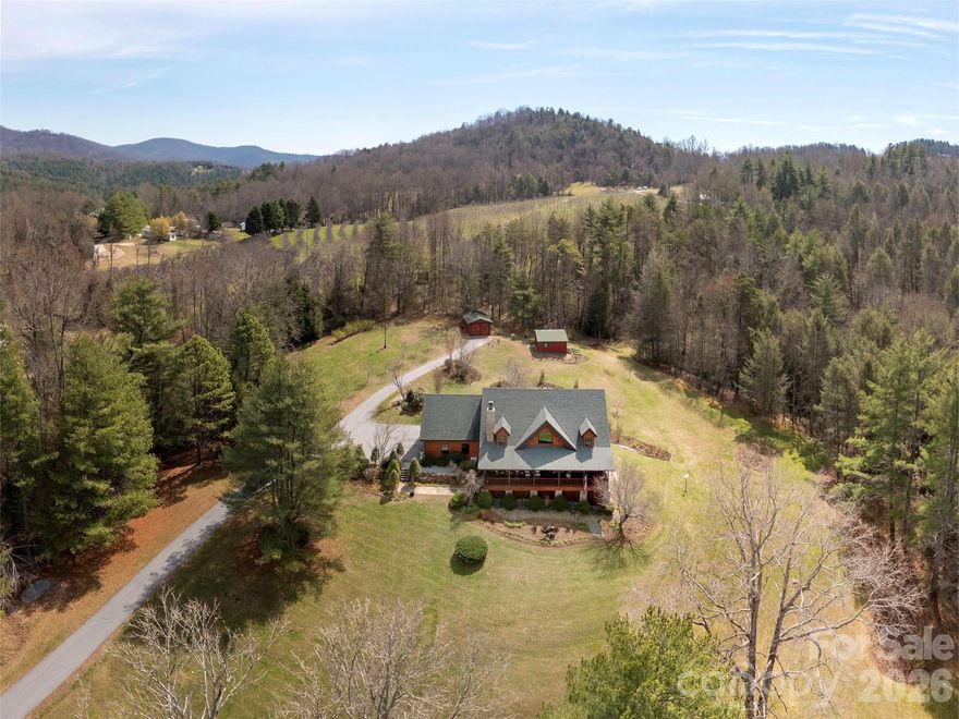 Experience refined country living with this exceptional custom log home, offering soaring ceilings and an elegant stone wood-burning fireplace in the great room that seamlessly connects to the dining area. The gourmet kitchen is equipped with an island, granite countertops, premium stainless steel appliances, and dual pantries. The main level features a spacious primary suite with a walk-in closet, while the upper loft provides an ideal setting for a home office, complemented by an additional large bedroom and versatile flex space. Spanning 9.45 acres, the property includes a barn, tractor shed, and dedicated workshop building, all accessed via an impressive steel bridge entrance. Enjoy covered porches at the front and rear of the home, and take advantage of an unfinished basement well-suited for a workshop or hobbies. Features include a whole house standby generator and a closed circuit security system. This private retreat blends comfort, functionality, and sophistication in a picturesque setting. Historic Main Street, shopping and endless possibilities for recreation are nearby!