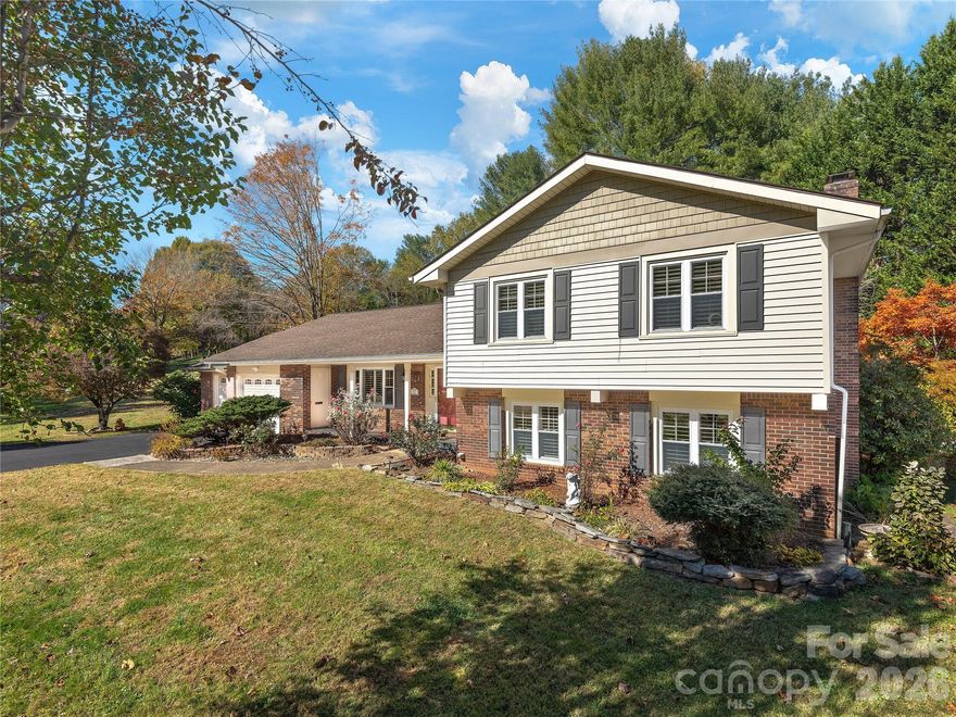 This thoughtfully updated split-level residence offers three bedrooms and a flexible bonus space suitable for a home office or fourth bedroom. The primary suite features an updated en-suite bath, and all baths have been improved to reflect modern functionality and enduring design. Interior details include hardwood flooring, crown molding, wainscoting, decorative trim, a wood-burning stove and newer carpet, showcasing meticulous upkeep and ongoing investment in the home. Natural light fills the home on all levels, enhancing daily living and entertaining. The eat-in kitchen provides ample cabinet space with a functional layout for gathering. The home has been lightly lived in for a few months each year and carefully maintained and updated to support ease of ownership. The half-acre landscaped homesite offers inviting outdoor living spaces for hosting guests and gardening. Additional highlights include an 859-square-foot two-car garage with workshop and abundant storage. Aproximately 15 minutes from downtown Asheville, with convenient access to hiking, recreation and local attractions, and less than a mile from Enka High School and the public pool.