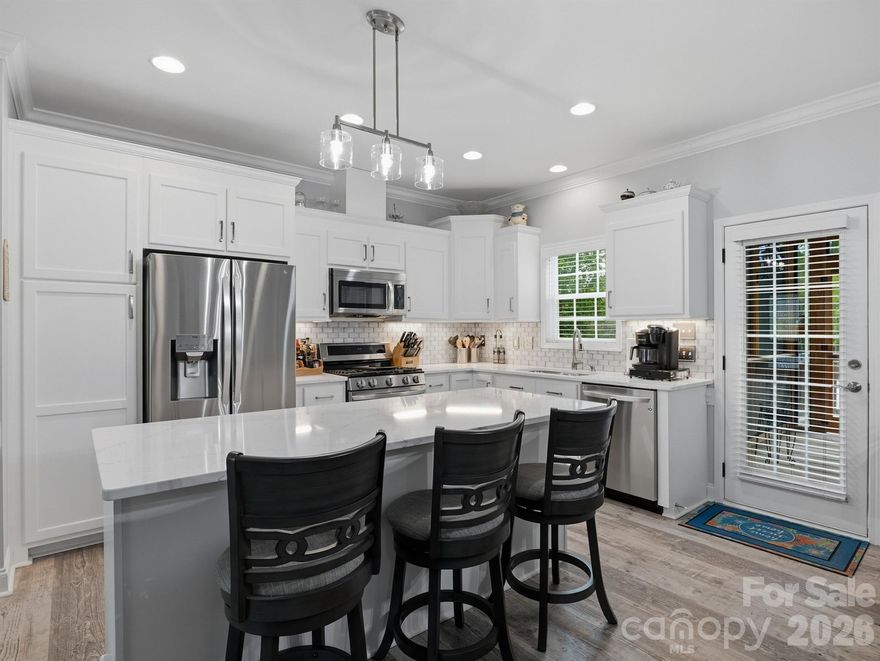 Beautifully maintained waterview home offering a perfect blend of quality construction, thoughtful upgrades, and exceptional outdoor living. This inviting residence features 9-foot ceilings with elegant crown molding and 2-inch blinds throughout, complemented by durable waterproof LVP flooring for a seamless, modern look. The well-appointed kitchen showcases upgraded cabinetry, quartz countertops in both kitchen and baths, and a spacious quartz island with breakfast bar—ideal for casual dining or entertaining. A charming breakfast area with chair rail adds character, while newer appliances, including a gas range and LG refrigerator, provide both style and function. The cozy living area features a gas log fireplace, perfect for relaxing evenings. The primary suite offers a private retreat with a transom window, dual quartz vanities, a beautifully tiled glass-enclosed shower, and a walk-in closet. Convenience continues with an LG washer and dryer included in the laundry room. Outdoor living is truly exceptional with a 35’ x 12’ screened sunroom, custom two-tier paver patio with fire pit, and under-deck utility storage. Enjoy peace of mind with Leafguard gutters, a 25-year sealed deck with warranty, and in-ground irrigation. Built with 2x6 framing for enhanced durability and efficiency, the property also includes a 24’ x 16’ insulated, fully finished with heating and air, outbuilding complete with vaulted ceiling, skylights, and sink—perfect for a workshop, studio, or flex space. *CPI security system will only remain with the property if Buyer agrees to take over the remaining contract. A rare opportunity combining waterviews, upgraded finishes, and outstanding indoor-outdoor living—this home is a must-see! NO HOA!