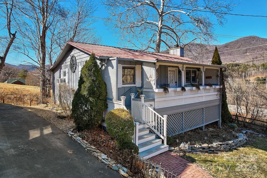 Charming 2BR, 2BA cottage nestled in Maggie Valley, with easy paved access and stunning year-round mountain views. Enjoy the serene ambiance with a rushing mountain stream right outside your door. This cozy retreat features wood floors (tiled in baths), and a cozy gas fireplace in the living room. The home is being sold fully furnished and ready to rent (short term rentals allowed) The bonus sunroom is the perfect spot for a mountain sunset to watch & listen to the bordering stream or step out to the back deck area. The front porch is covered & offers a welcoming entry to the home. There is plenty of storage in the crawl space & the backyard is fenced. The neighborhood offers a community pavilion space and a metal roof to keep the maintenance costs down. Centrally located just minutes to downtown Maggie Valley, 10 minutes to Waynesville, 12 minutes to the Blue Ridge Parkway, and 20 minutes to Cherokee.