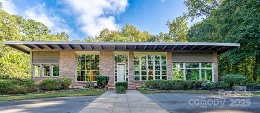 Hidden in plain sight, this mid-century gem welcomes you with floor-to-ceiling windows, 15' ceilings, refinished oak floors, and a double-sided flagstone fireplace. The gourmet kitchen features a 48" Wolf gas range, a Sub-Zero refrigerator, four Fisher & Paykel dishwasher drawers, and a separate Sub-Zero ice maker. The guest wing's 40' hallway leads to two bedrooms with en-suites and walk-in cedar closets, while the opposite wing houses the primary suite with a fireplace and a large walk-in closet. Both wings open to a Japanese-inspired garden leading to an infinity pool with a covered bar, outdoor fireplace, grilling stations, and a full bath. A separate four-bay garage with conditioned shop space awaits you. It sits on 11+ acres, featuring a wooded perimeter, an irrigation system, and an enclosed hobby garden. Accessible via a private drive, this gated, fenced oasis awaits you. There is the ability to reconfigure/expand the current space, and/or build an ADU (accessory dwelling unit)