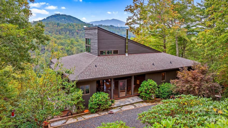 For the very first time, this remarkable masterpiece is available to the public — a rare opportunity to own a Doug Sigler-designed home, crafted with the vision and artistry that define his legacy in Western North Carolina. Known for his ability to merge architecture with nature, Sigler created a timeless retreat at 496 English Lane that feels both elevated and deeply connected to the land. Set on 34+ private acres, the home captures sweeping mountain & river views while offering unmatched peace and privacy, with additional potential homesites throughout the property that also enjoy elevated view corridors. Walls of glass, soaring ceilings, and a handcrafted timber frame interior bring warmth and strength to the design. Expansive decks and terraces invite quiet mornings, starlit evenings, and seamless indoor-outdoor living. Inside, the main level offers a dramatic great room anchored by a stone fireplace, with open dining and kitchen spaces, plus a light-filled loft above. A finished lower level with a kitchenette extends the living space, and a detached studio with a full bath, skylights, and a private deck provides a creative haven or guest suite. A whole-house generator ensures comfort and peace of mind in every season. Trails wind through the property to the North Toe River, while the internationally renowned Penland School of Craft—a vibrant hub for artists and makers—is just minutes away. Cherished by one family since its creation, this estate embodies art, architecture, and Appalachian beauty in perfect harmony.