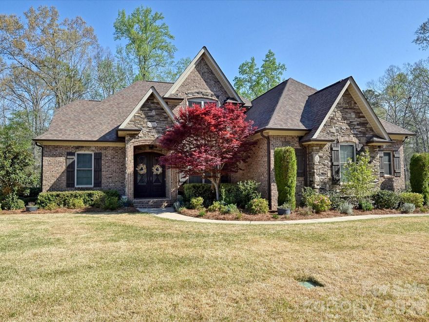 Exceptional Living Space, Style and Serenity!  Welcome to this timeless all brick & stone feature-rich home!
Beautifully maintained, offering 3,591 sq ft of living space, thoughtfully designed for comfort, flexibility and everyday luxury. Set on just over an acre of land in a highly desirable amenity-rich community near Lake Wylie. Offering living at its finest with privacy, space and room to grow!  The interior of this home boasts a chef’s gourmet kitchen which features a gas range, pot filler, double oven, stainless steel appliances, stand-alone ice maker, farmhouse sink, granite countertops, cabinets and counter space galore. The open concept living room, brings a warm focal point to the home with a large gas fireplace and gorgeous built-in cabinets. The primary bedroom with upgraded LVP flooring and ensuite can be found on the main level which includes expansive his & her walk-in closets. Enter through the impressive French doors on the main level to a flexible room that can be used as an office, library or formal dining room. Finally, a functional laundry and ½ bath all on the main floor. Beautifully maintained hardwood floors shine throughout the main level leading to the three-car garage with built-in shelving. The basement level has unfinished space with a garage door for cars, tractors, workshop, man-cave, she-shed and a ½ bath.  Climbing the curved oak staircase to the upstairs, you will find upgraded LVP flooring in all bedrooms and living areas, three generously sized bedrooms, and two more full baths. 

Enjoy the outside of this property where privacy and space abound. The expansive fully fenced backyard is ideal for pets, child play and entertaining. Easy access to the ½ bath makes outdoor entertaining wonderfully convenient. Wander through an abundance of garden features, including: apple, peach, and fig trees, a pawpaw tree, blueberry, blackberry, and raspberry bushes, flower beds and herbs. Zoysia grass in the front lawn provides low maintenance with a front yard irrigation system. Peace of mind comes with your new home in a hard-wired security system and central monitoring. This home comes with two lots/parcels and therefore two HOA Boat/RV storage spaces on site, twice the storage of most homes!  Award winning Clover schools to include the new state of the art schools set to open in Fall of 2026, and this home has been re-zoned for these amazing schools beginning in fall of 2026. For school information visit: https://www.clover.k12.sc.us/o/district/page/student-reassignment-2025

Life here provides easy access to Lake Wylie for boating, fishing, sun and fun! Easy access to downtown Charlotte and CLT International Airport. Many small trendy restaurants and shopping is nearby to enjoy, as well as malls and grocery stores for your everyday needs.

This amazing home seamlessly blends space, functionality and lifestyle – offering the freedom of acreage and the convenience of community amenities, with the comfort of thoughtfully upgraded interiors. Whether you are entertaining, gardening, working from home or just simply enjoying a quiet evening by the fire, this property delivers a rare combination of flexibility, charm and class.   Come see it today and call it HOME!