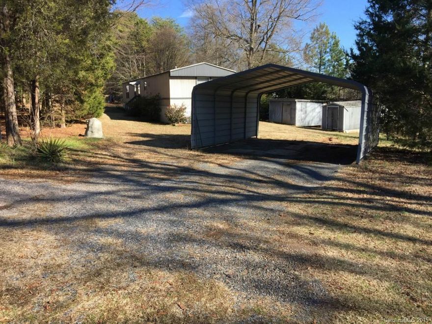 Tranquil tree lined parcel of just under an acre featuring a two bedroom mobile home, carport, and outbuildings.  Sale is AS-IS.