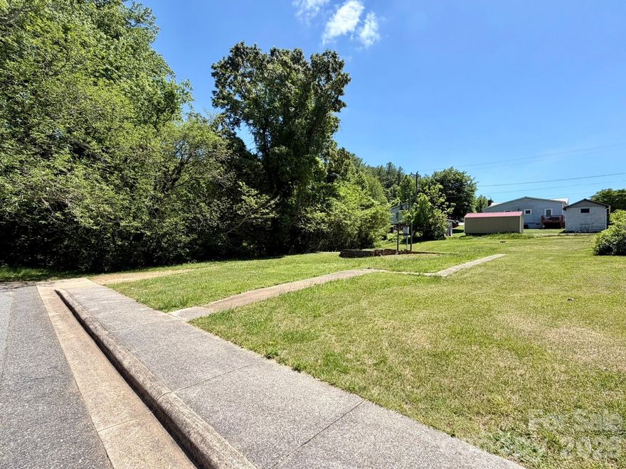 Rarely found in the mountains, 100 4th Street offers an exceptionally level homesite within city limits—an uncommon opportunity in Western North Carolina. With public water and sewer available, zoning for site-built or modular construction, and existing improvements including a former garage slab and walkways from the original homesite, the property offers an unusually easy path to building. Sidewalk frontage and a quiet street setting add to its in-town appeal. Beyond the lot itself, its location in Marion makes this offering even more special. Often regarded as one of the region’s most picturesque small towns, Marion is cherished for its historic downtown, pedestrian-friendly streets, mountain-framed scenery, nearby greenways and recreation, with Lake James just a short drive away and Asheville within easy reach. Opportunities to build on a flat, ready-to-improve homesite in a town this charming are increasingly rare.