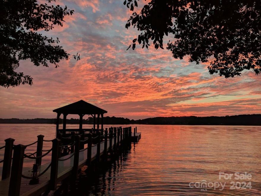 This exceptional waterfront property offers breathtaking sunrise and sunset views overlooking Lake Norman's main channel. The interior showcases luxurious details, including a floating staircase with wrought iron spindles, arched windows, and custom millwork throughout. The gourmet kitchen is a chef’s dream, featuring lighted curio cabinets, a built-in refrigerator with cabinet-front drawers, and a cozy keeping room. The two-story great room is a showstopper, with a wall of windows and French doors that perfectly frame the lake views, complemented by a custom-designed fireplace with a marble hearth. The second floor boasts a secondary primary suite with sliding doors leading to a veranda overlooking the water, a third bedroom with a private ensuite bath, and a spacious bonus room with abundant walk-in storage. **Ample attic/storage available upstairs offering expansion opportunity for additional bedroom if needed. Outside, enjoy BIG WATER VIEWS from the private pier w/charming gazebo.