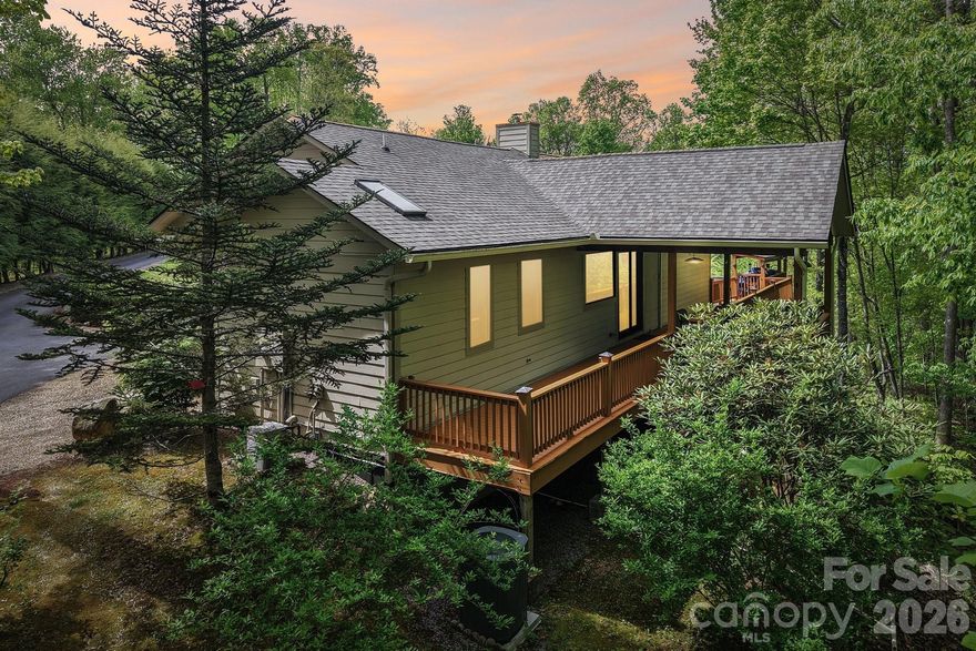 This unique, well-maintained, custom upscale mountain home sits on 3.59 private wooded acres with close mountain views, striking rock work, and numerous custom finishes. A gated entrance and paved driveway lead to the spacious, single-level residence featuring an oversized primary suite with a soaking jacuzzi tub, separate shower, large walk-in closet, and an additional closet. The split-bedroom layout places the guest suite on the opposite side of the great room, which boasts cathedral wood ceilings, an open floor plan, and a dining area. The custom gourmet kitchen is equipped with stainless steel appliances, breakfast bar, wine refrigerator, built-in pantry, and opens to a covered deck ideal for entertaining, as well as an open deck perfect for morning coffee. A fireplace with insert and abundant windows create an open, airy feel. Outside, a detached two-car garage sits near a large workshop with electricity and hot water, separate from the main house. Adjacent to the shop is a heated and cooled studio apartment with full bath and kitchenette. Additional features include a heated greenhouse with fans and skylights, camper canopy, extra carport for vehicles or recreational equipment, and a storage shed. Located in a private wooded community of distinctive homes, this property offers proximity to Mars Hill shopping, dining, and breweries, just 8 minutes to I-26 and 10 minutes from Hatley Pointe Boutique Ski Resort and Wolf Laurel Community. A truly exceptional mountain retreat.