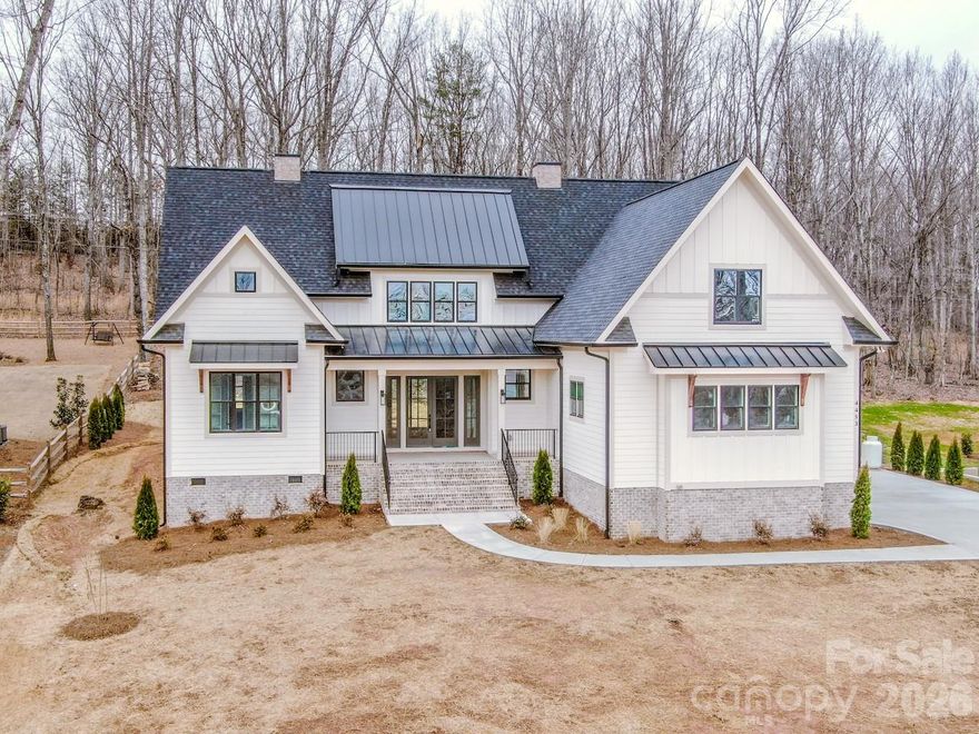 You'll be immediately impressed upon entering this quality built new construction modern farmhouse, complete with all the bells and whistles on nearly an acre – No HOA and room for a pool! This stunning 4-bedroom, 3,672-sq-ft home has an open floor plan, is flooded with natural light and is perfectly situated on a private 0.93-acre wooded lot, on a beautiful picturesque dead-end street, in the highly desirable North Lincoln School District, just minutes from North Lincoln High School. Designed with exceptional construction and attention to detail, this quality-built home blends timeless craftsmanship with elegant modern style and an open, light-filled layout perfect for everyday living and entertaining. Inside, you’ll find crown molding, wainscoting, engineered hardwood floors, oak stair treads with LED lighting and 8-foot interior doors throughout. Every room showcases custom trim work, built-ins, designer lighting and high-end finishes, creating a sense of sophistication and warmth. The chef’s kitchen is the true heart of the home, featuring floor-to-ceiling white soft-close cabinetry with upper glass doors, beautiful tile work, brushed gold fixtures, a white farmhouse sink and an oversized 9x5 shaker-style island with seating and storage. A professional 48-inch range with double oven and a direct vent hood anchors the space, while the adjoining scullery includes additional shaker cabinetry, a sink, dishwasher, tile backsplash and pocket door—providing the perfect hidden prep area for entertaining. Beautiful backsplashes, custom shelving and a spacious dining area complete this impressive culinary space. The family room is warm and inviting, highlighted by a gas fireplace with a gorgeous vertical fluted accent wall, custom wood mantel and a stunning ceiling fan, all overlooking the tranquil wooded backyard. The main-floor primary suite offers a luxurious retreat with a trim accent wall, ceiling fan and spa-like bath featuring a freestanding soaking tub, walk-in tiled shower, dual vanities and a large walk-in closet with custom shelving. A laundry room connects to both the primary suite and hallway, offering a sink, upper and lower cabinetry, and ample storage. An office/flex room with double glass doors and backyard views provides the perfect space for working from home, hobbies or reading. A main-level full bath with a walk-in shower is conveniently located for guests or multi-generational living. Upstairs, you’ll find three spacious bedrooms, a loft with built-in desks and bookcases, bonus room and a second laundry area for added convenience. Two of the bedrooms are connected by a thoughtfully designed Jack-and-Jill bathroom, where each bedroom enjoys its own private vanity and toilet, with a shared tiled tub/shower between. The third upstairs bedroom has access to a beautiful hall full bath with a tiled walk-in shower, ideal for guests. The versatile bonus room provides space for a media room, gym or play area, while the loft is perfect for studying, gaming or relaxing. Outdoor living shines in this home’s spectacular backyard retreat. The covered back patio features a stained wood ceiling with ceiling fans, providing a stylish place to relax or entertain. The expansive, level yard offers ample space for a pool, garden or play area, surrounded by the peaceful privacy of mature trees. Professional landscaping includes seed, straw and shrubbery. Additional highlights include black & white windows, additional side entry door, brushed gold fixtures in the kitchen & primary suite, black fixtures in secondary baths, custom trim work and built-in details throughout that elevate this home’s timeless design. The side load finished garage has been wired for electric vehicle charging. This home offers the perfect blend of luxury, privacy, and convenience.  Conveniently located minutes from Hwy 150 & Hwy 16 offering easy access to Denver, Lincolnton, Mooresville, medical, restaurants, golf and the airport.