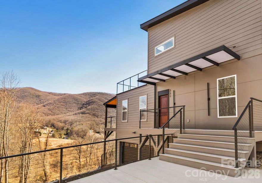Stunning mountain-view contemporary home on a private 1.06-acre lot just minutes from Asheville. This 2,958 sq ft residence offers 4 bedrooms, 3 full bathrooms, and a spacious 2-car garage. Thoughtfully designed, it combines refined design with everyday functionality. Filled with natural light, the open layout features expansive windows, high ceilings, and a bright, inviting atmosphere. The main level includes a spacious living area, modern kitchen, laundry, and two bedrooms. Upstairs, the primary suite offers a private retreat with a well-appointed bath and direct access to a large sun deck — perfect for peaceful mornings or sunset evenings. Over 650 sq ft of covered porches and outdoor decks create a seamless indoor-outdoor lifestyle, ideal for both relaxing and entertaining. Located in a quiet, safe community just 5 minutes to I-40 and 20 minutes to West Asheville.