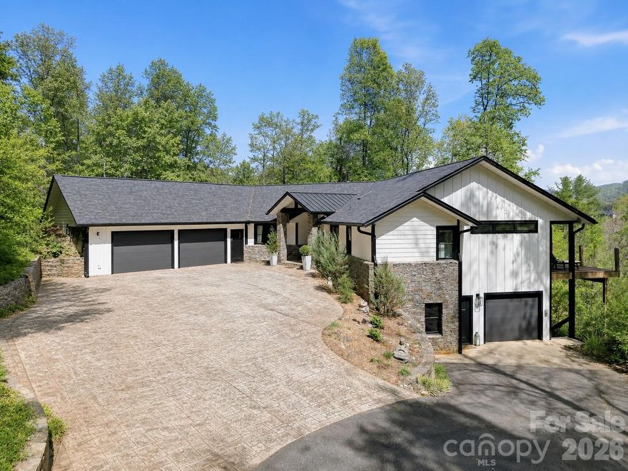 Set across approximately 12.5 +/- acres of unspoiled, unrestricted, mountain terrain, 169 Pickens Road presents a strikingly elevated take on contemporary living—where refined design meets the quiet beauty of the Blue Ridge landscape. Ideally positioned just a short drive from both downtown Asheville and the charm of Weaverville, the setting offers a seamless balance of privacy and accessibility.

The residence has undergone an extensive transformation, showcasing a clean, modern aesthetic defined by expansive glass, intentional sightlines, and light-filled interiors that frame sweeping, long-range mountain views. Recent improvements—including a newly installed roof and additional thoughtful updates throughout—enhance both the home’s appeal and long-term peace of mind.

Inside, the main level unfolds with impressive volume and fluidity, connecting living, dining, and kitchen spaces in a way that feels both sophisticated and inviting. The kitchen itself is designed as both a focal point and a functional workspace, blending streamlined finishes with everyday practicality. Radiant heated and cooled flooring spans both levels, delivering year-round comfort with understated luxury.

Two well-appointed primary suites offer private, spa-like retreats, while additional flexible spaces provide versatility for guests, work-from-home needs, or creative use. The lower level reveals a distinctive entertaining experience—a hidden speakeasy complete with a custom wine cellar and full bar, creating an intimate atmosphere unlike anything else.

Complementing the main residence is a detached studio positioned above a single-car garage, offering a private and inspiring space ideal for artistic pursuits, a home office, or continued use as a creative studio. With its separation from the main home, this structure also presents an excellent opportunity for conversion into an accessory dwelling unit, adding both functionality and long-term value.

Outdoor living is equally compelling, with four separate decks positioned to capture the surrounding mountain vistas, including a secluded deck directly off the primary suite. Beyond the home, the property unfolds into a landscape of rolling meadow and wooded acreage, complete with a network of private trails and a serene, tucked-away pond that enhances the sense of retreat. These trails wind gracefully throughout the property, offering an immersive way to experience the land—whether for horseback riding, ATV or dirt bike adventures, or quiet evening walks surrounded by nature.

On top of all of this - the sellers are offering an extended home warranty until September of 2028 to truly give you peace of mind. Additionally - the home is being offered furnished as a separate option! This is an opportunity to step into a fully realized mountain estate—where modern luxury, natural beauty, and intentional design come together in a truly exceptional way.