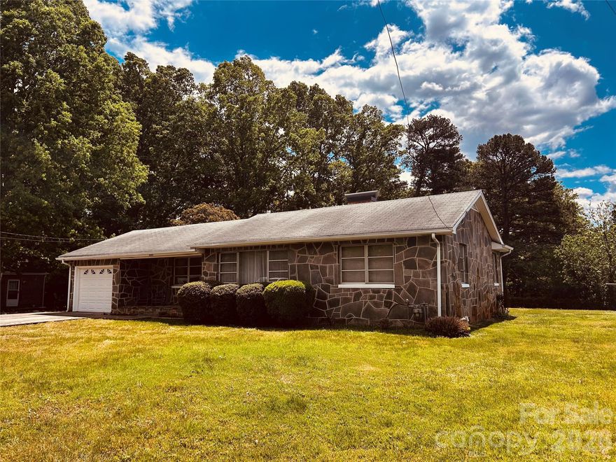 Quaint stone cottage home located just minutes from everything Hickory has to offer.   This home was lovingly built by the former occupant and his father in the late 1950's.   Quality stone work on the outside invites you to step onto the front porch.   Enter into the Living Room with stunning knotty pine walls and a corner crab-apple stone fireplace with woodstove insert.  There is also a gas wall heater for added heat.  Adjoining the LR is a cozy Den/Study also with knotty pine walls.   Step into the large kitchen with handmade knotty pine cabinets.  From the kitchen, access the single garage.  A back porch is accessible from the Living Room and overlooks a huge backyard, complete with storage building.   Two bedrooms and a full bath complete this special home.  The stone work is wonderful - the cellar has stone flooring.  Home is on city water and sewer - well and septic on property are no longer used.  
Seller has shared this history of the home:  "The house was constructed in 1957 by our grandfather Patrick Stephens and our father, Dale Stephens. Patrick was a renowned stone mason in the Catawba Valley, having worked on numerous houses in the area during this era. This stonework was handcrafted and unique, with a handful of similar homes that can still be found in the local area."