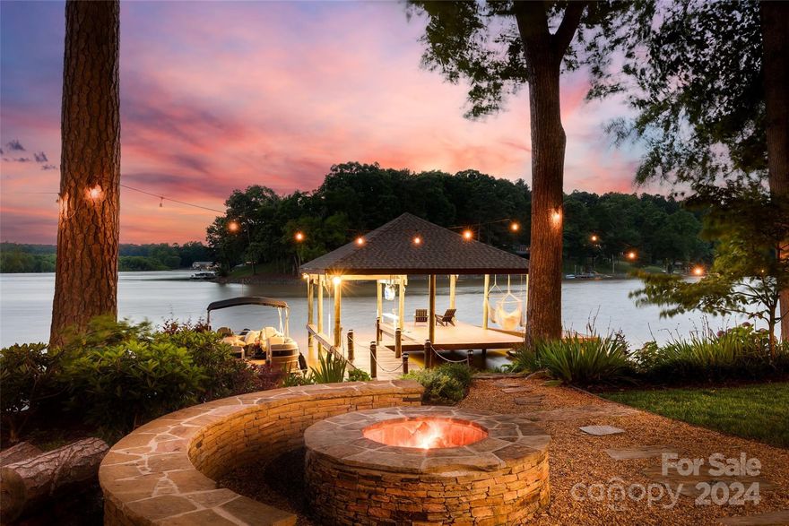 Entertainers Dream Home! Experience unparalleled luxury living at this magazine-worthy lakefront estate on Lake Wylie. Boasting a sprawling flat lot; a rarity; this home offers an immaculate landscaped site with breathtaking sunset views throughout. Wake up to the serene beauty of the lake from the large primary suite on the main floor. The remodeled kitchen, complete with an entertainer's island, flows seamlessly into the dining room, perfect for hosting gatherings with the lake view as your backdrop. The basement level features a kitchenette, family room with pool table, theater, office, and exercise room with a jetted hot tub. Step outside to your own private resort adorned with a pool and a separate pool house equipped with a built-in barbecue, kitchenette, and dining area overlooking the lake. With a boat dock accommodating several boats, a jet ski pad, canoe launch, fire pit, and resort-style amenities, every day feels like a vacation at this unparalleled lakefront retreat.