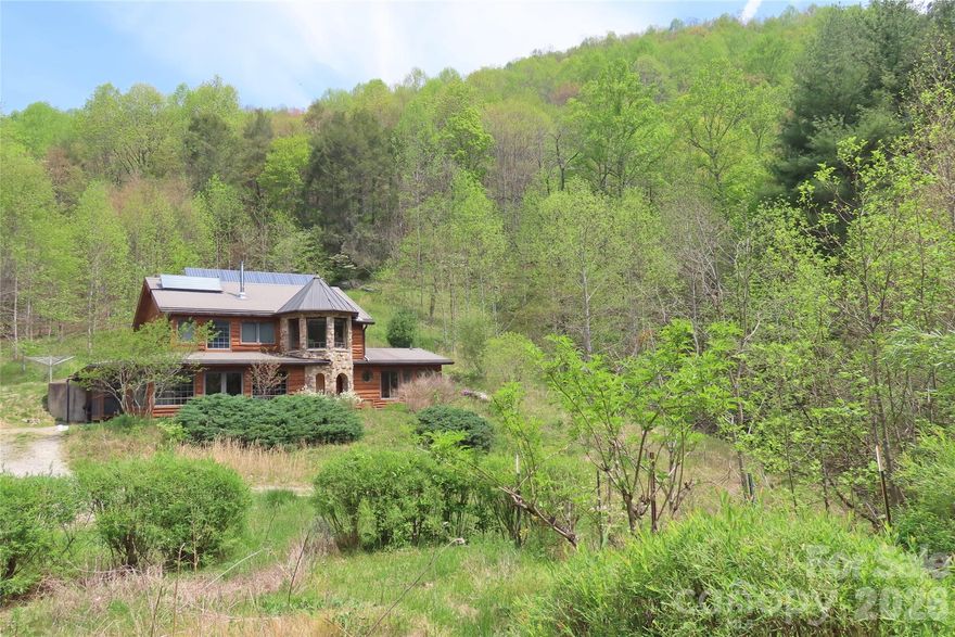 This custom off-grid home is a truly one-of-a-kind mountain homestead, tucked into a secluded meadow on 23.98 acres of mixed woodland and partially fenced, flat pasture. Sunny, south-facing open areas offer excellent space for gardening, orchards, or small-scale farming. A confluence of two creeks borders walkable mountain forest with trails, mature trees, rocky outcroppings, and a spring that has never run dry. In the Bat Cave/Gerton area, where much of the land is steep, this amount of usable acreage is a rare find. Also located on the property are a historic cabin and a sturdy functioning barn with hayloft and stone silo, all over 100 years old, offering options for animals, storage, workshop space, or covered parking.

The 2126-square-foot passive solar home is filled with character, featuring more than 13 species of wood, including red oak, walnut, persimmon, and cherry, all locally sourced, much of it cut and milled by the builder. Built with true 2x6 framing, solid hardwood construction, custom trim and cabinetry, arched doorways, large timber beams, and built-in bookcases and benches, this home is an entirely unique work of craftsmanship. Gaze out over unbroken mountain views from the stone turret or from the upstairs bathroom’s clawfoot tub. An upstairs meditation room with miniature antique doors lights the floating stairway below through stained glass. This bermed-in home also includes a screened porch and three covered outdoor living areas.

Enjoy the peace and quiet of off-grid living with the radiant warmth of passive solar design, supplemented by a beautiful and efficient soapstone woodstove with glass viewing window. Water is heated by solar thermal with propane backup. The PV array is supported by meticulously maintained lithium batteries installed in 2022. The current owners designed the home, oversaw all construction and improvements, and can provide detailed plans for the home’s systems and construction.

Farmed and cherished for generations before the home was built in 2011, this property is centrally located in a neighborhood of helpful, highly skilled people who came together as a strong, self-sufficient community after hurricane Helene in 2024. Middle Fork Road, currently undergoing improvements, will again be fully paved up to the property. Accessible to Asheville, Hendersonville, and Black Mountain by a 35-minute drive, the property is also convenient to Chimney Rock, Lake Lure, and area hiking destinations.

The homesite itself is a private sanctuary of garden spaces, berries, flowering trees, native pollinator meadows, dark starry skies, and nights filled only with the calls of katydids and owls. Lovingly managed year after year, this nature lover's haven presents a rare opportunity to own a remarkable off-grid homestead in the mountains.

Seller proposes arranging a conservation easement collaboratively with buyer.