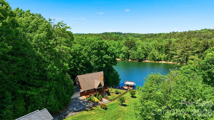 Beautiful Waterfront Retreat located on Lake Hickory! This thoughtfully designed residence offers approximately 3,300 sq. ft. of comfortable living space with 2-story views of the lake!  Located in a peaceful lakefront setting that's perfect for a weekend get-a-way or someone seeking a primary residence on the lake! Stepping onto the property, you'll feel the craftmanship is evident in every turn.  Natural wood textures, exposed beams, and warm stonework echo the surrounding setting!  The main level features a spacious great room with soaring ceilings, floor to ceiling windows overlooking the lake, wormy chestnut accents, and a grand stone wood burning fireplace. The open floor plan flows seamlessly into the dining area with a built-ins and chef’s kitchen, complete with custom cabinetry.  Additional main-level spaces provide a full bathroom with laundry closet, a main level bedroom for guests and access to the 2 car garage.  Step out onto the wrap-around deck to enjoy your morning coffee, the distant view of the railroad trellis as well as the change of seasons!  The upper level primary suite/loft is amazing!  It offers direct views of the lake and the main living spaces and a well-appointed bath area with separate vanities and walk-in shower.  The lower level features a large recreation room with fireplace, easy access to the outdoor living areas and waterfront, 2 rooms for quests, a small kitchenette and a 3rd full bathroom. Outdoor spaces include a fenced in yard with a beautiful walkway to the lake, a patio area with firepit, a storage shed for your lake toys, a large lakeside patio area and an expansive dock with boatlift.  The covered dock provides easy access to boating, swimming, fishing and all that Lake Hickory has to offer.  Conveniently located near Hickory's bustling downtown area, walking and biking trails on Hickory's City Walk and River Walk, local restaurants, breweries, and shopping!  An easy drive to the NC mountains for skiing, hiking and more. About an hour's drive to Charlotte Douglas Airport!