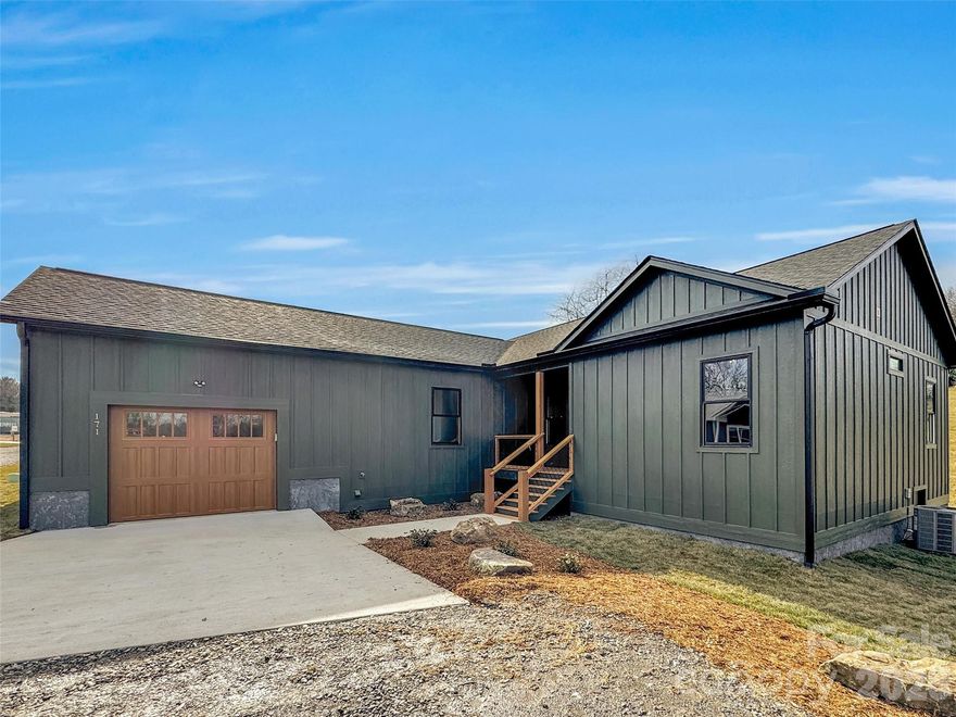 High-quality new construction meets effortless one-level living at 171 Peyton Elaine Rd, conveniently located with easy access to Canton, Waynesville, and I-40. This thoughtfully designed 3BR/2BA home offers 1,560 sq ft of open, light-filled space with a desirable split-bedroom layout and vaulted ceilings that elevate the main living and dining areas. LVP flooring runs throughout the entire home, creating a clean, cohesive, and low-maintenance living environment. The kitchen is both striking and functional, featuring granite countertops, black stainless appliances, and an accent wall that anchors the space. Retreat to the spacious primary suite, complete with walk-in closets, tiled shower, double vanity, and another custom accent wall that adds warmth and character. Outdoor living is equally inviting with a screened-in rear porch and beautifully landscaped grounds, while the oversized one-car garage offers impressive 12' ceiling height, providing added functionality and storage. Positioned on a corner lot at the end of the road, the home enjoys enhanced privacy within this well-planned community. Ideal as a low-maintenance primary residence, a lock-and-go second home, or a rental-friendly investment opportunity. One of the final opportunities to own in this new community—schedule your showing and experience it before it’s gone!