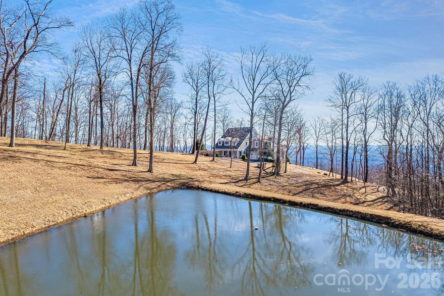 Welcome to 11 By the Wayside, an exceptional mountain retreat nestled on just over 10 private acres in the quiet and serene White Oak Mountain community. Offered fully furnished and turnkey, this home invites you to arrive, exhale, and immediately begin enjoying the mountain lifestyle.

The thoughtfully updated kitchen and main living area flow seamlessly onto a covered veranda, where sweeping, unobstructed mountain views create a stunning backdrop for entertaining or evenings immersed in nature. Inside, the home has been impeccably maintained and offers five spacious bedrooms, four and a half baths, a formal dining room, and a warm, inviting den—providing generous space for hosting family and friends.
Begin your mornings on the covered rocking-chair front porch, coffee in hand, overlooking your private pond. From the moment you turn onto the tree-lined driveway, the sense of privacy and tranquility sets this property apart.

Additional features include an unfinished third-floor walk-up offering abundant storage or future potential. Residents of White Oak Mountain enjoy access to over 400 acres of preserved green space, seven+ acres of water, three scenic ponds, and a community picnic area—an unparalleled setting for outdoor living.
All furnishings, electronics, artwork, washer and dryer, refrigerator, and new custom shades convey with the home, making this a rare move-in-ready mountain escape. Fireplace conveys as-is with no known issues.

A true mountain sanctuary—private, scenic, and effortlessly livable. Please use provided directions; GPS is not recommended. Coming from Tryon, take a right on Houston Road. Take a left on White Oak Mountain Road and drive approximately .3 miles up the mountain. Make a left on Hemlock Trail (it will say private road) and stay left 1.7 miles to 11 By the Wayside located on left. Home is nestled on the top of White Oak Mountain, so please note, you will be driving up the mountain.