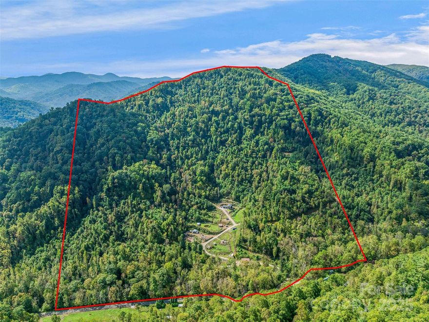 Discover 100+ acres of privacy, freedom, and opportunity at 945 Roaring Fork Road in Hot Springs, NC. Perfect for those seeking off-grid living, sustainable farming, or a private mountain retreat, this unique property sits on part of the Pisgah National Forest and includes part of Cud Gap. With abundant wildlife, natural springs, blackberries, and miles of trails, it’s ideal for hiking, mountain biking, 4-wheeling, hunting, foraging, or simply enjoying the beauty of nature. At the heart of the property is a custom-built home with a jacuzzi and superior foundation walls, heated floors, tiled showers, deep soaking tub, granite countertops, stainless steel appliances, a 100-gallon water heater with boiler hookup, and spray foam insulation. Mountain views enhance the comfort and design, while a garage adds convenience. 

Multiple additional dwellings and structures expand the possibilities: An unpermitted tiny container home with deck, granite countertops, and mini split. Mobile home with outdoor fireplace (personal property). Climate-controlled greenhouse with radiant heat, hot water heater, and fan. Root cellar, garden area, two chicken coops, goat barns,  plus a pond and creek with beach area. 

For work, storage, or creative projects, the property offers: Shop/Garage #1 with 200-amp electric panel. Shop/Storage #2 with a wood stove, two storage containers, and a hydroelectric system. Infrastructure supports expansion, including a future build site with slab, roughed-in plumbing, and additional unpermitted septic, plus other potential build areas. This property is perfectly suited for a family compound, homestead, farm, or nature lover’s escape. 100 acres ensure lasting privacy to live sustainably, play freely, and create your legacy on this one-of-a-kind mountain property. Motivated seller, bring an offer!