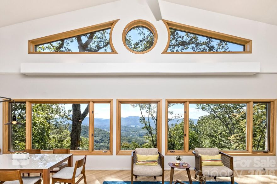 Perched high above the surrounding landscape and tucked into more than 8 private acres, this one-of-a-kind modern mountain retreat offers a rare combination of architecturally bold design, energy efficiency, and breathtaking natural beauty. Designed with a striking triangular footprint, the home is thoughtfully positioned to capture panoramic, layered views of the Blue Ridge Mountains from nearly every angle—creating a constantly changing backdrop of light, color, and season for your life.

Surrounded by mature hardwoods, mountain laurel, and rhododendron, the setting feels completely secluded, with no visible neighbors and a true sense of escape. A gated driveway reinforces the property’s privacy making it ideal as a serene full-time residence or lock-and-leave getaway. 

Inside, the home features an open floor plan, cathedral ceilings for natural light, and a dramatically designed geometry. Expansive windows draw the outdoors in, framing long-range mountain vistas and filling the space with morning sunlight, while afternoon shade from the surrounding trees keeps the home naturally cool.

Built with efficiency and sustainability in mind, this passive solar home was built to offer lower utility costs. Features include a Tulikivi soapstone thermal wood stove, energy-efficient gas fireplace, HRV ventilation system, and multiple heating options that blend comfort with performance. Whole house generator.

The main level supports one-level living, while a finished walk-out basement provides flexible space for guests, multi-generational options, and recreation. Thoughtful details such as built-ins, a Murphy bed, hardwood and tile flooring, and a modern kitchen with quality finishes further elevate the home’s livability.

Outdoor living is just as compelling. The deck and viewing vistas take in the unobstructed, long-range mountain views—often described as “above the clouds.” The Fairview Forest acreage itself has a "remote sanctuary" feel, with hiking trails, natural beauty, wildlife protection, with well-maintained roads for your safer winter access. 

Located just 24 minutes from Pack Square downtown Asheville. Easy access to Blue Ridge Parkway, Black Mountain, and I-40, this property delivers the rare balance of complete privacy with convenience for dining, culture, and outdoor adventure.

A truly distinctive home—architecturally bold, environmentally thoughtful, and immersed in nature. HOA is at https://www.FairviewForest.com/