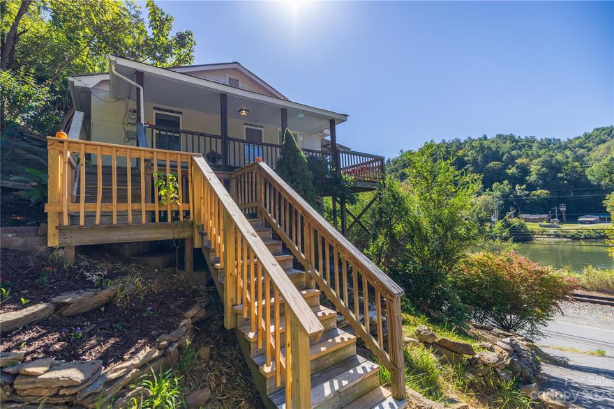 Newly renovated fantastic Marshall cottage with sweeping view of the French Broad River ! Awesome turn key  vacation rental with solid history.  River Rock Cottage sits on  4.84 beautiful acres with opportunities for additional home sites.  Old house site on ridge still holds bricks from the foundation and other relics. City water and sewer. Small stream and multiple boulders on property. Great views on the French Broad from the covered front porch. Easy walk to quintessential downtown Marshall .  Great hiking, biking and river sports all around.   Railroad right of way extends from road to river but area can be used for parking and fishing. No permanent structures allowed .