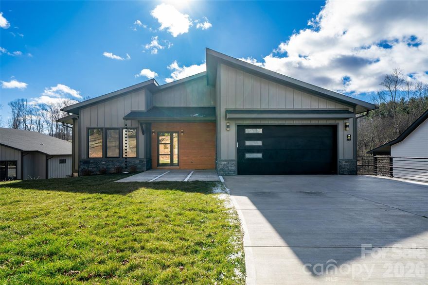Designed for buyers who want style now and flexibility later, this refined one-level new construction delivers light-filled living with soaring ceilings, clean lines, and seamless indoor-outdoor flow. The designer kitchen anchors the home with a quartz waterfall island, premium appliances, custom cabinetry, and generous pantry storage. Retreat to a spa-inspired primary suite featuring a statement shower, soaking tub, and serene finishes. Four covered patios frame the natural setting and expand everyday living. Below, a 2,700 sq ft unfinished basement with 12-foot ceilings offers endless possibilities—guest suite, home office, gym, media room, or rental potential. Seller can finish lower level upon request. No HOA restrictions, outside the flood zone, and minutes from Asheville’s best amenities.